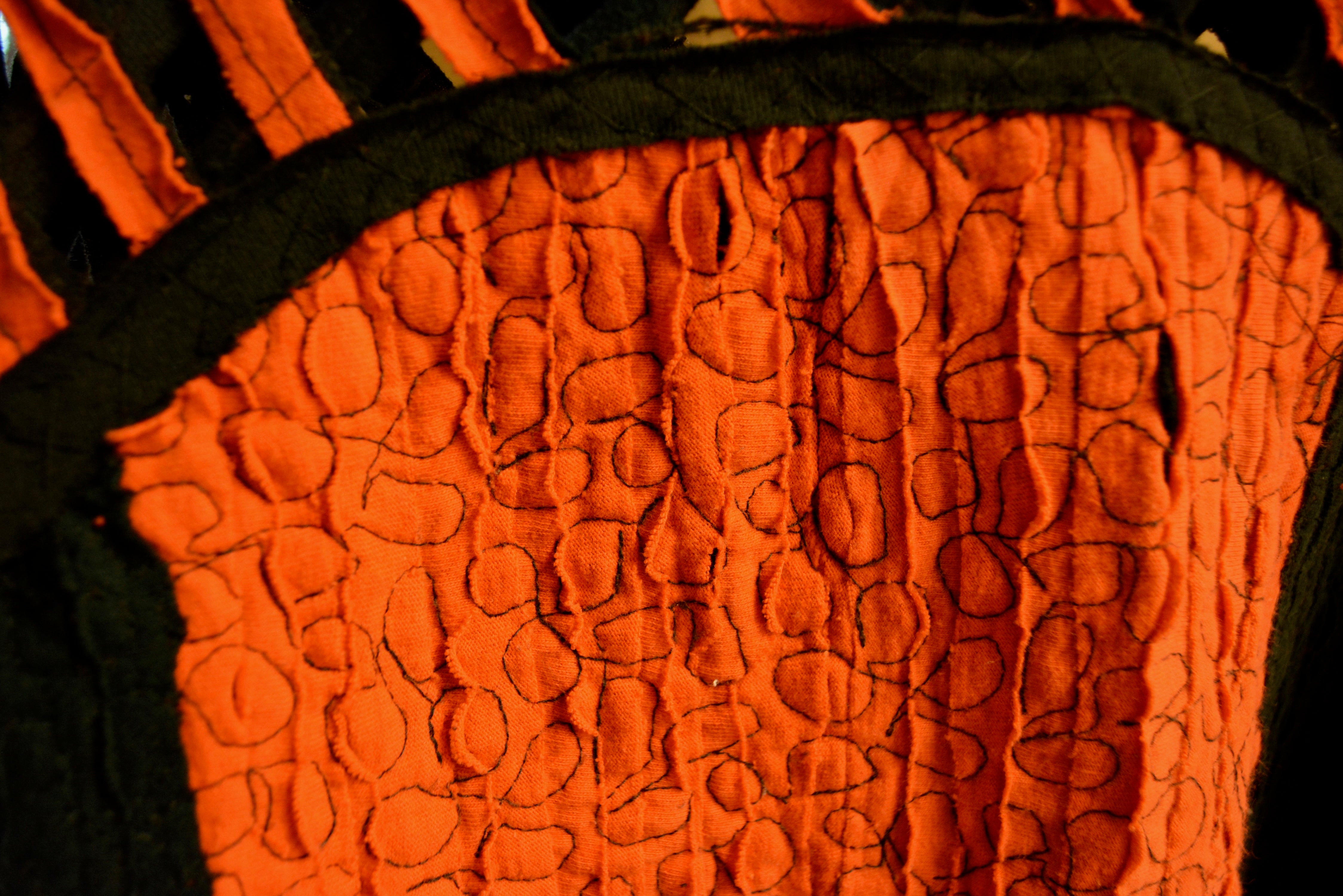 Close up of orange fabric with black embroidery detail